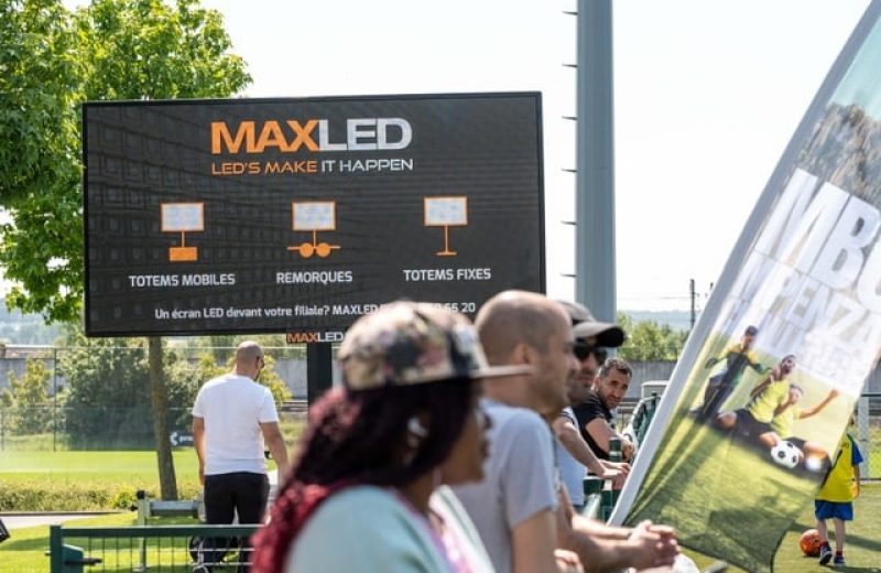 Grand écran LED mobile de Maxled au bord d’un terrain de football, avec des spectateurs devant
